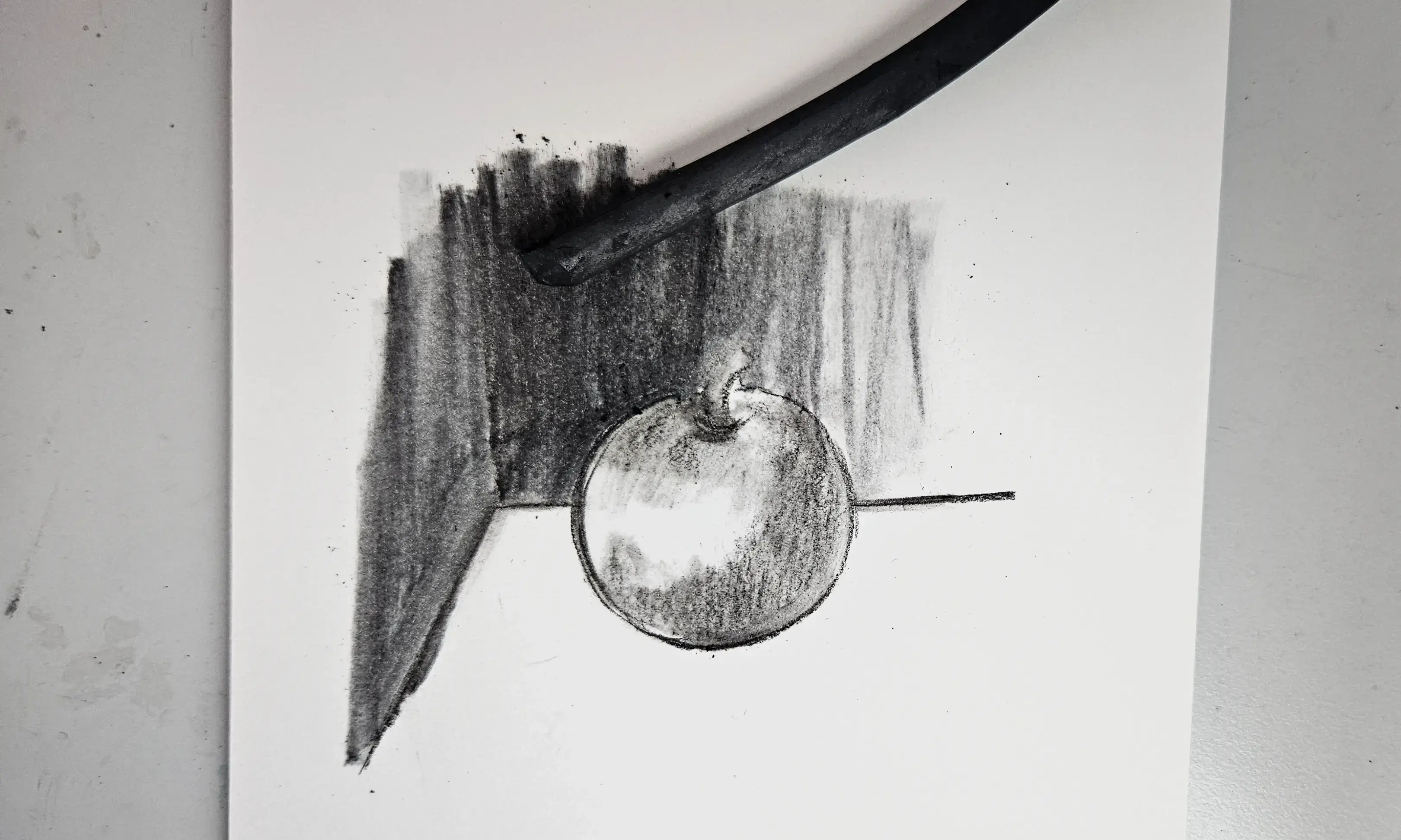charcoal drawing of an apple contrasted against a wall
